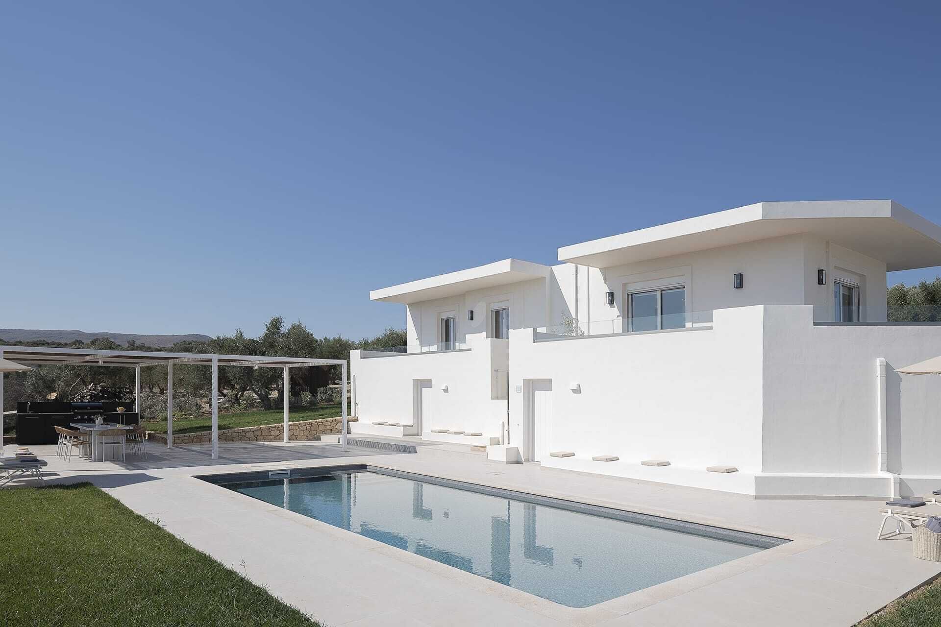 Una moderna casa a due piani con piscina, area relax all'aperto e vista panoramica sul paesaggio circostante.