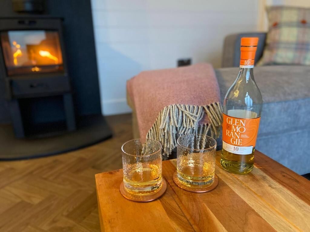 Una botella de Glenmoan Ransom sobre una mesa de madera con dos vasos.