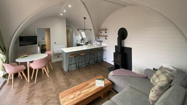 Un espacio habitable compacto con área de cocina, mesa de comedor y asientos.