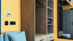 A room with a sofa, a wooden wardrobe, a mirror, and a thermostat on the wall. - Axis Hotel (Trabzon)