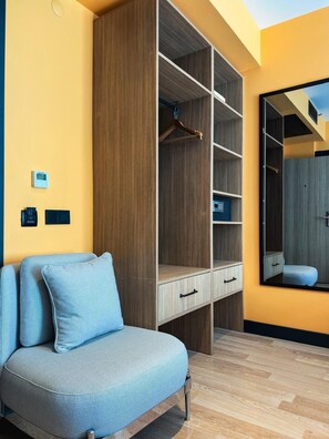 A room with a sofa, a wooden wardrobe, a mirror, and a thermostat on the wall. - Axis Hotel (Trabzon)