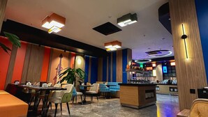 Un moderno vestíbulo de hotel con zonas de estar, un bar y una recepción.
