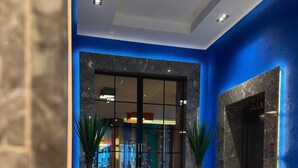A hotel lobby with a glass door entrance, a reception desk, and a digital elevator display. - Axis Hotel (Trabzon)
