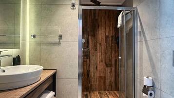 A modern bathroom with a glass shower enclosure, a white sink, and a blue bathtub.