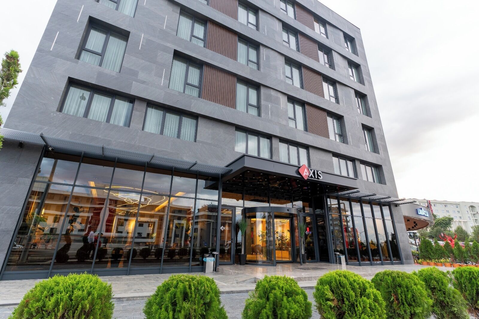 A multi-story hotel with a glass facade, a covered entrance, and a sign reading 'AXIS'.