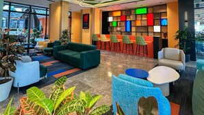 Un lobby moderno con techo verde, zonas de estar y un bar de decoración colorida.