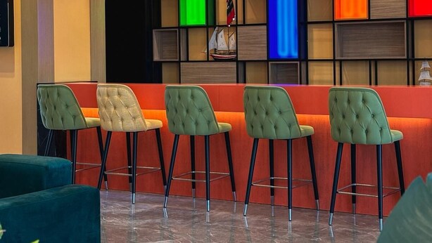 Un vestíbulo moderno con zona de bar, asientos y una pared decorativa.