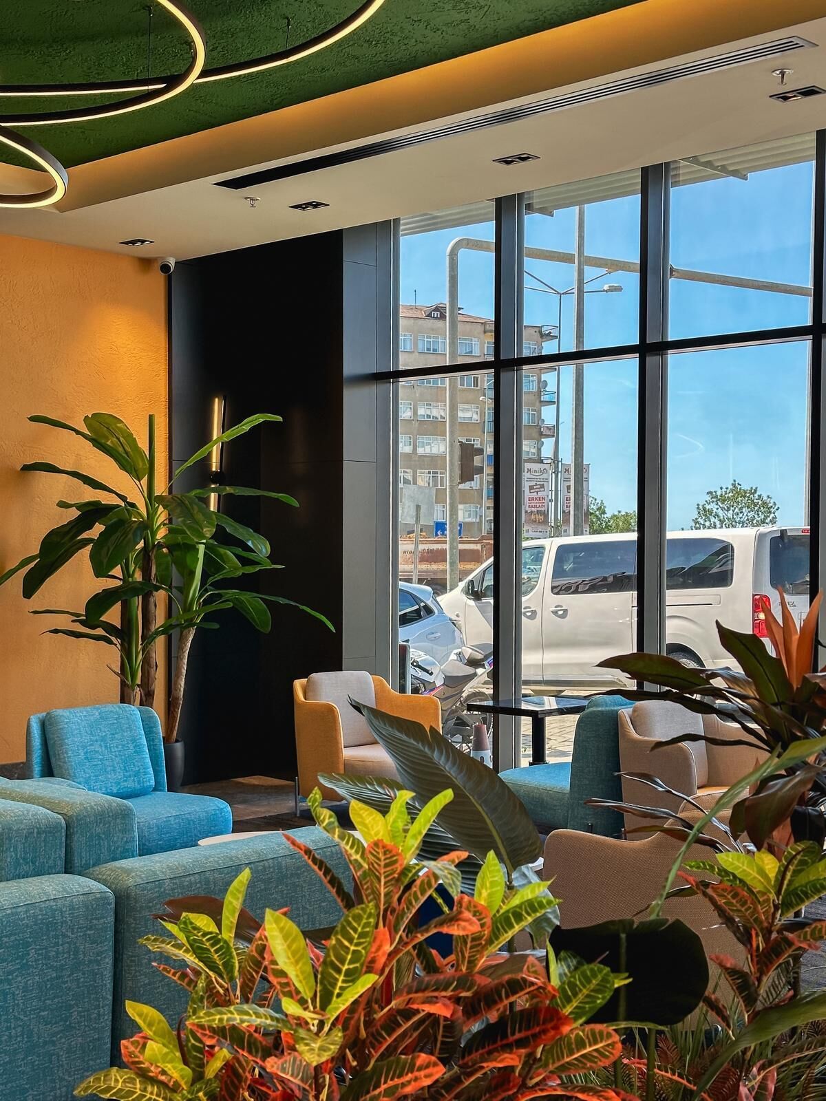 A modern interior with seating, large windows, and indoor plants.
