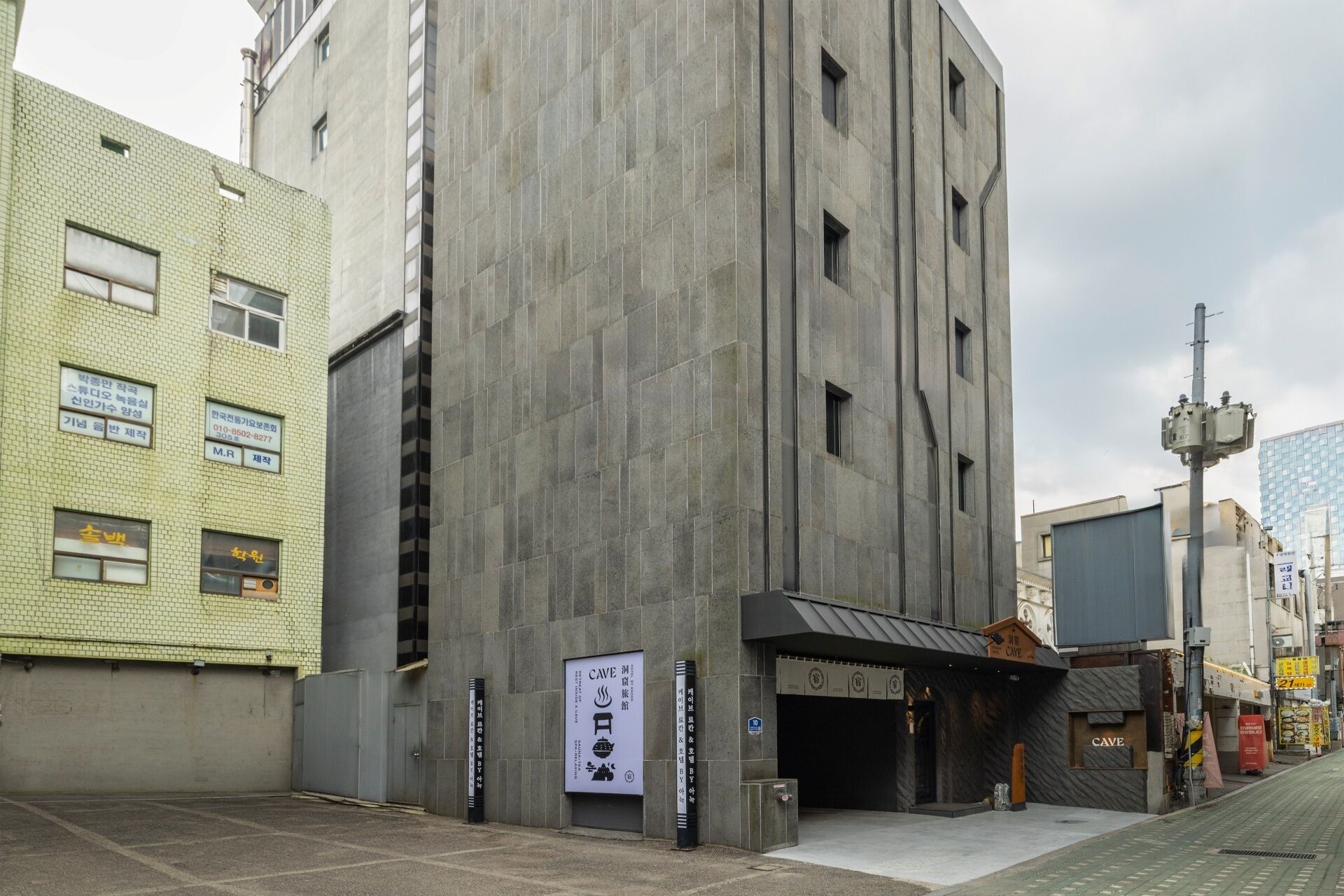 A modern building with a concrete facade, a covered entrance, and a sign for a cafe.