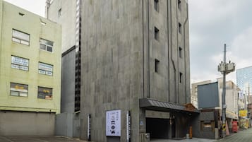Un bâtiment moderne avec une façade en béton, une entrée couverte et une enseigne indiquant la présence d’un café.
