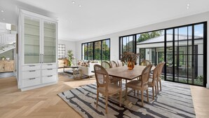 A spacious living area with a dining table, chairs, and a large window offering a view of the outdoors. - Belle Grove (Cape Town)