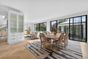 A spacious living area with a dining table, chairs, and a large window offering a view of the outdoors. - Belle Grove (Cape Town)