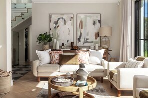 A modern living room with a sofa, armchairs, a coffee table, and abstract paintings on the wall. - Belle Grove (Cape Town)