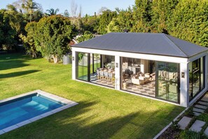Ein modernes Haus mit Wintergarten, Schwimmbad und gepflegtem Rasen.
