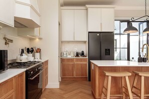 Een moderne keuken met houten kasten, een roestvrijstalen koelkast en een centraal eiland met krukken.