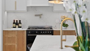 A modern kitchen with a gas stove, wooden cabinets, marble backsplash, and a white countertop. - Belle Grove (Cape Town)