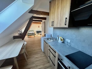 Una cocina compacta con armarios de madera, un horno empotrado y una encimera con una tetera.