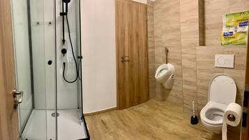 A bathroom with a glass shower enclosure, a toilet, and a bidet.