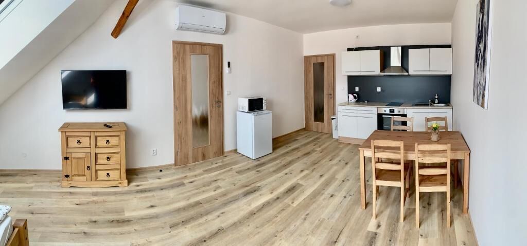 A modern kitchen with white cabinets, a microwave, and a dining area with a wooden table and chairs.