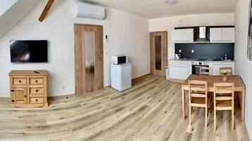 A modern kitchen with white cabinets, a microwave, and a dining area with a wooden table and chairs.