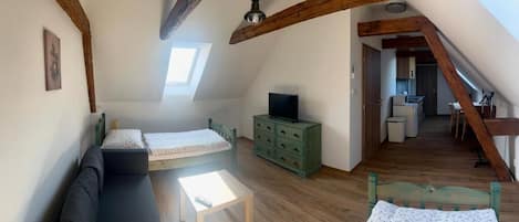 Et loftstudie med en alkove-seng, en sofa, en kommode og et fjernsyn.