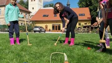 A group of people playing croquet on a grassy field with a church in the background.