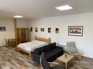 A room with a bed, a sofa, a chair, a small table, and a cabinet.