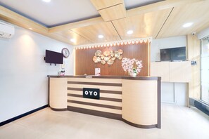 A reception desk with a clock and a TV above it.