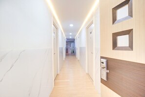 Un pasillo de hotel con piso de mármol, puertas de madera y una lámpara moderna.