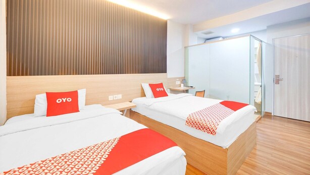 Ein Hotelzimmer mit zwei Betten, einem Holz-Kopfteil, einem Nachttisch, einem Spiegel, einem Kleiderschrank und einem Badezimmer mit Dusche.