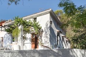 A white building with a tiled roof, a wooden door, and a window with bars.