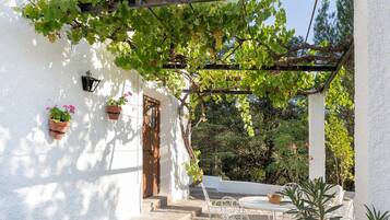 Un bâtiment blanc avec une porte en bois et des marches menant à un patio couvert.