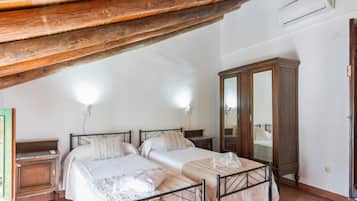 Un dormitorio con dos camas, un armario de madera y un equipo de aire acondicionado.
