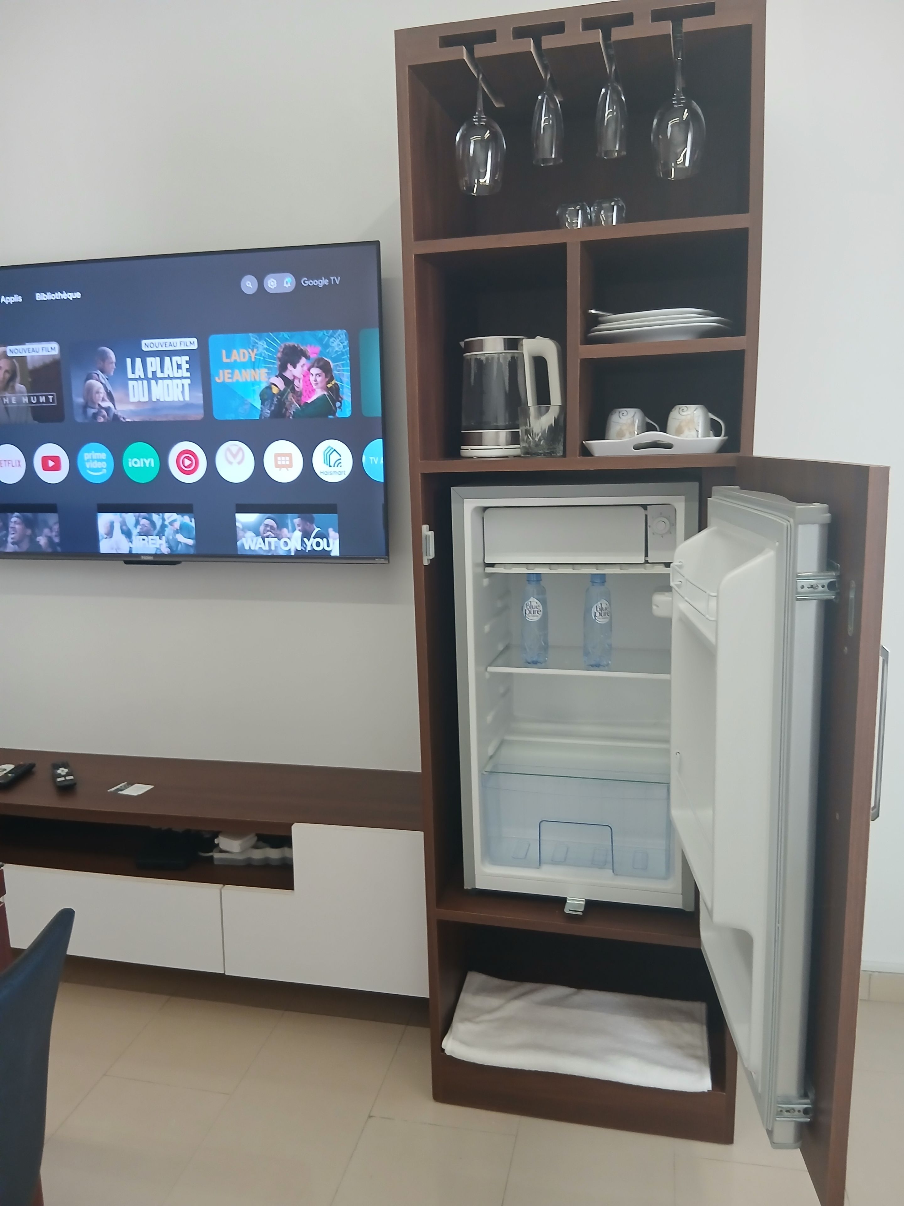 A compact kitchenette with a refrigerator, a coffee maker, and a wine glass holder.
