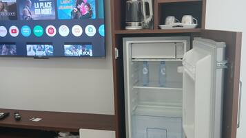 A compact kitchenette with a refrigerator, a coffee maker, and a wine glass holder.