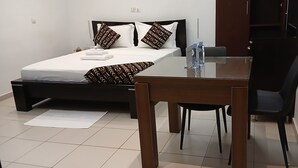 Een slaapkamer met een bed, nachtkastje, stoel en een bureau met stoel.