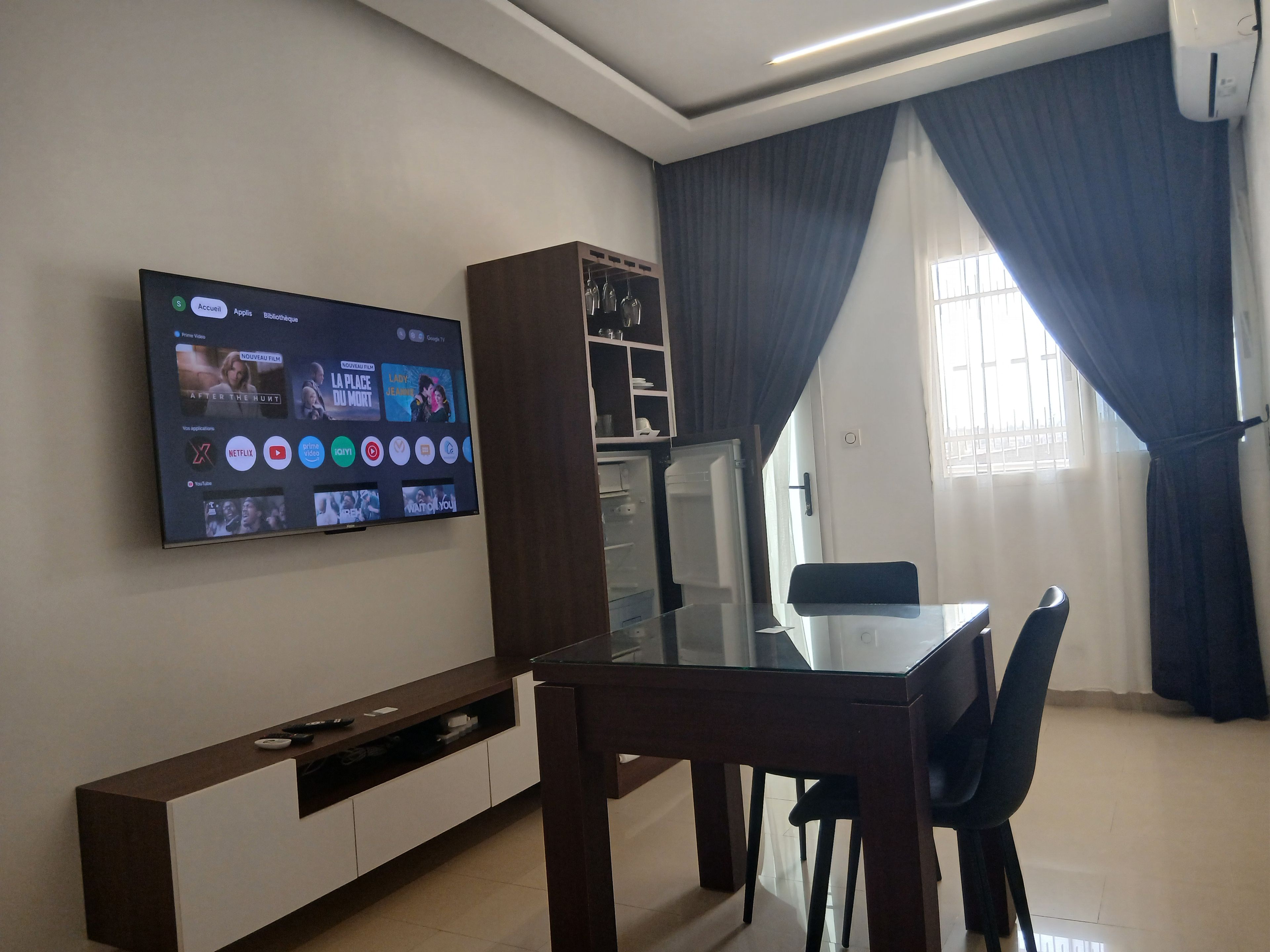 Una sala de estar moderna con un televisor de pantalla plana montado en la pared que muestra varios servicios de transmisión.