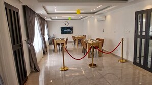 Een hotel lobby met een modern design, met een receptiebalie, een zithoek met tafels en stoelen, en een grote televisie aan de muur.