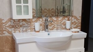 Een badkamer met een witte wastafel, een grote spiegel en een douchecabine.