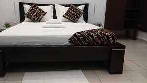 Een moderne slaapkamer met een groot bed, een donker houten hoofdbord, witte beddengoed en gestreepte kussens.
