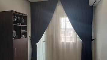 Una habitación con ventana, armario y aire acondicionado.