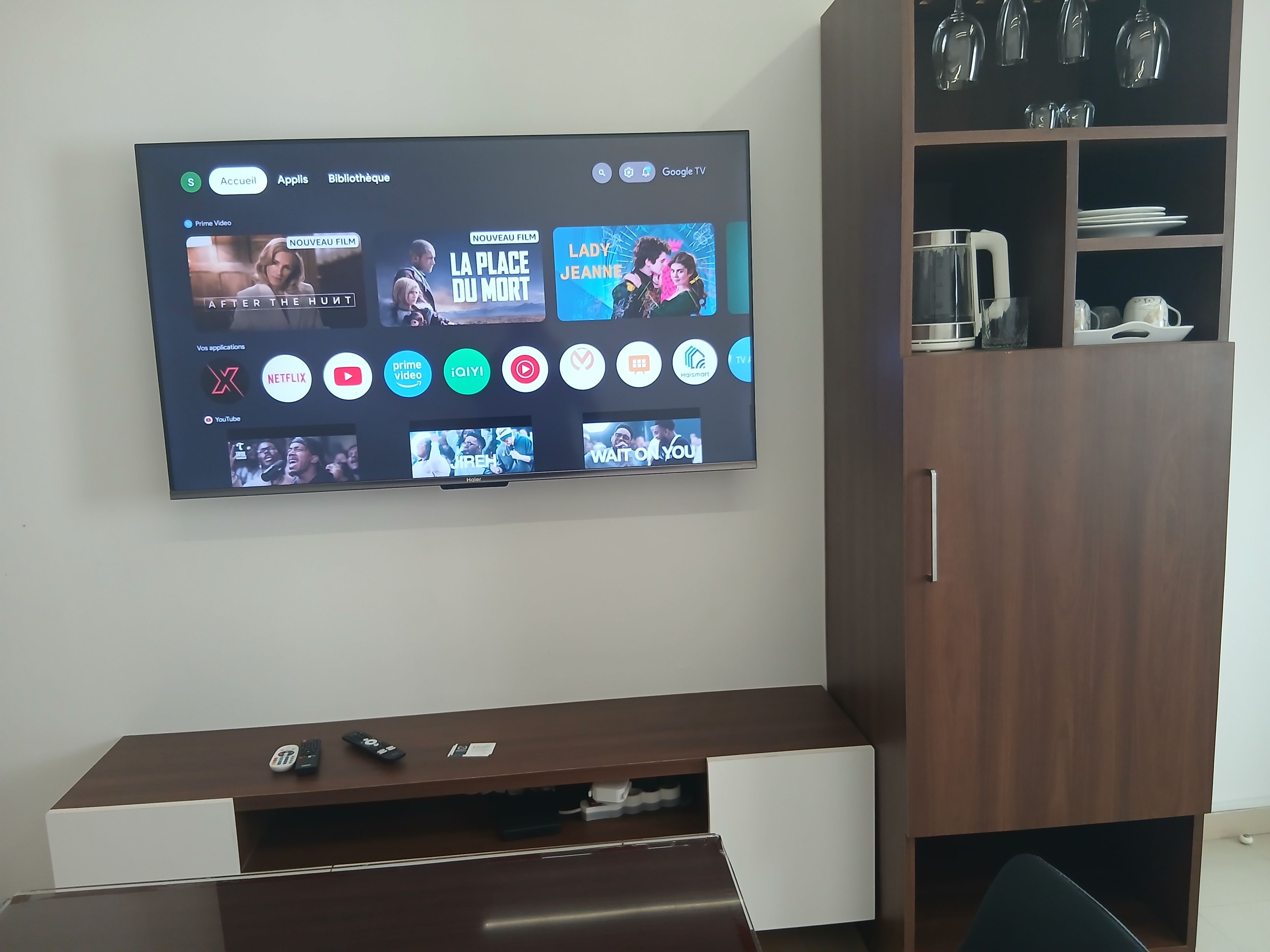 A flat-screen TV mounted on a wall displaying various streaming services and content.