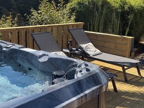 A hot tub with two lounge chairs and a wooden deck. - Charming House in Névez – Spa, Sauna, Pool, and Rospico Beach Within Walking Distance (Névez)