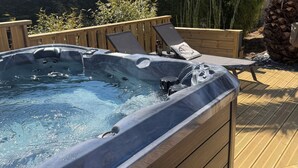 A hot tub with two lounge chairs and a wooden deck. - Charming House in Névez – Spa, Sauna, Pool, and Rospico Beach Within Walking Distance (Névez)