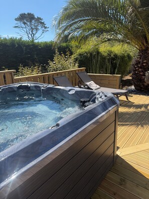 Ein Whirlpool mit zwei Liegestühlen und einer Holzterrasse.