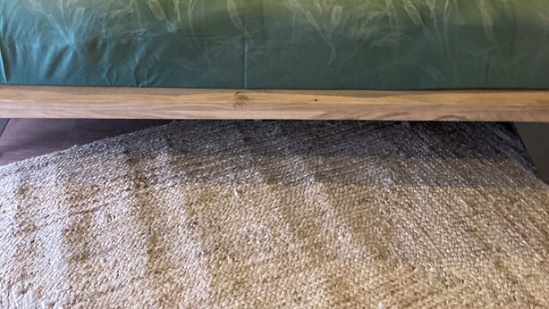 A bed with a wooden frame, green bedding, and a beige blanket. - Charming House in Névez – Spa, Sauna, Pool, and Rospico Beach Within Walking Distance (Névez)