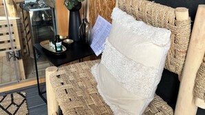 A room with a woven sofa, a small table with a black tray, a potted plant, and a wooden door. - Charming House in Névez – Spa, Sauna, Pool, and Rospico Beach Within Walking Distance (Névez)