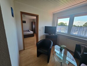 Una stanza con un letto, una televisione, un tavolino in vetro con una pianta e una finestra vista.