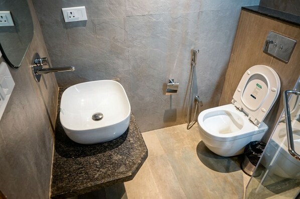 A modern bathroom with a white sink, a toilet, and a shower. - Hotel Layover Stay-3 Minutes From the Airport (Jaipur)