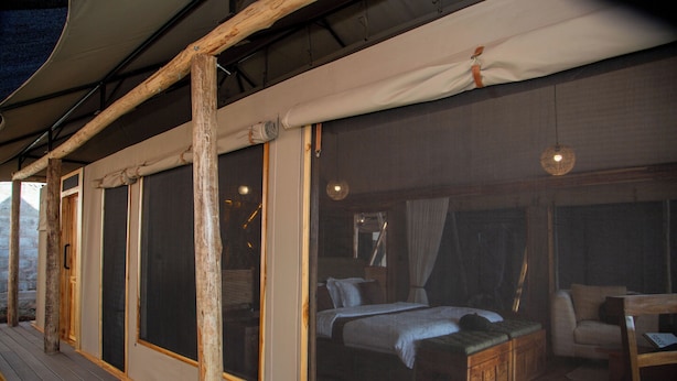 Una stanza con un letto, una sedia in legno e una lampada a sospensione.